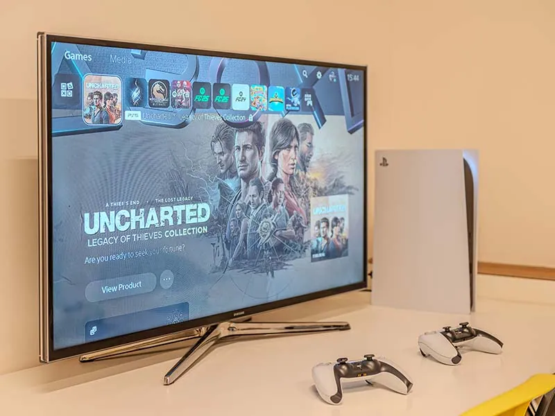 Кинозона в Bro-coli Palmovka с телевизором, PlayStation 5 и двумя геймпадами на столе