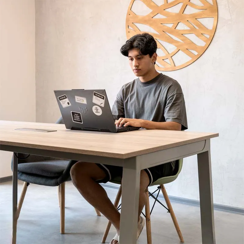 Young man working on a laptop at a wooden table in a quiet co-working room