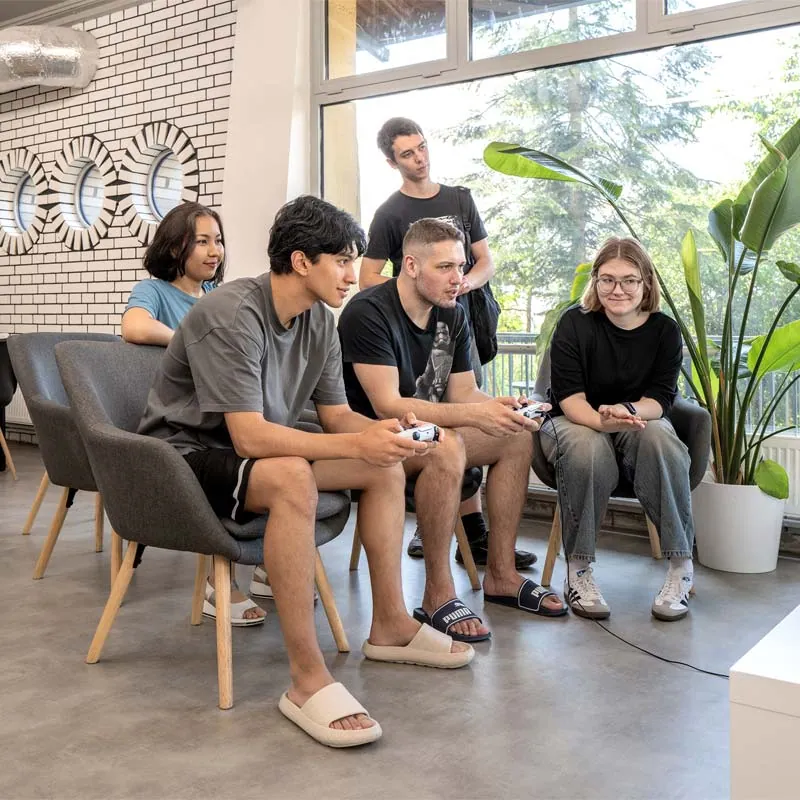 Friends playing a video game with controllers in a bright lounge with large windows
