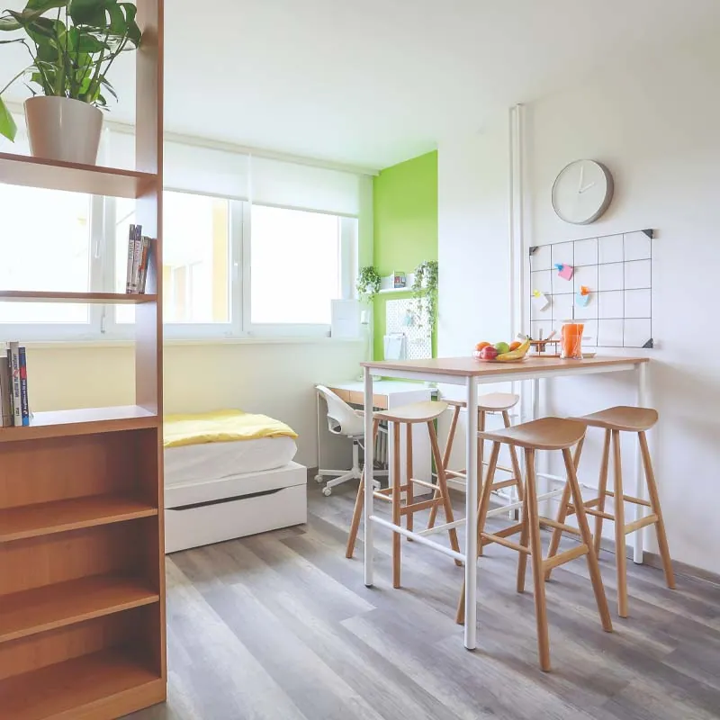 Bright Bro-coli room with a bed, desk, bookshelf, bar table with stools and a lime-green accent wall